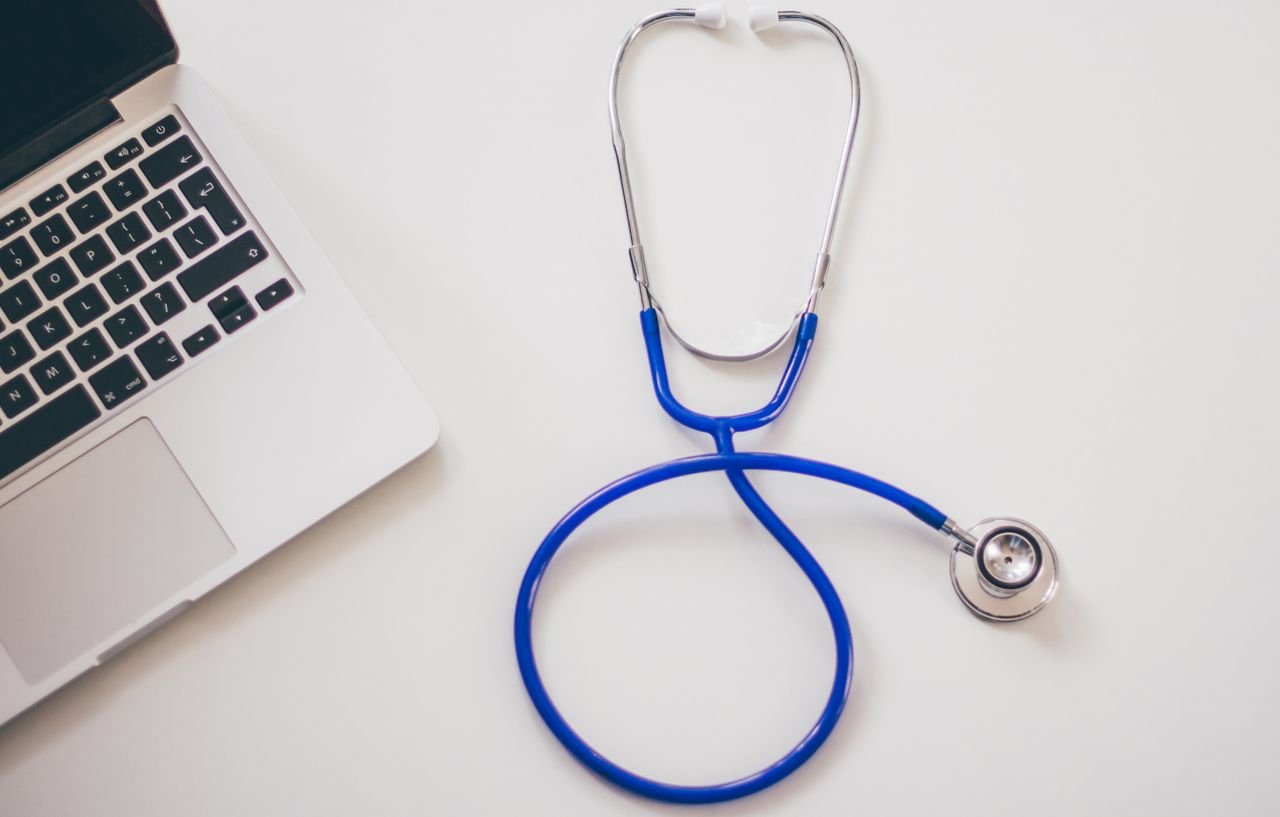 footer-cta-img Medical stethoscope and laptop on a white desk, symbolizing digital health solutions.