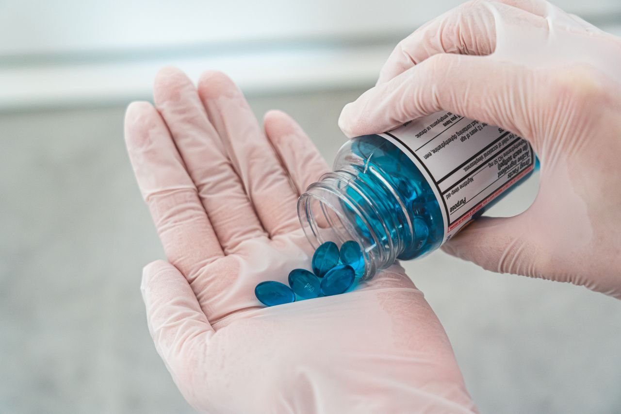 Mastering the First Impression: Your intriguing post title goes here Gloved hands carefully pouring blue oval pills from a prescription bottle.